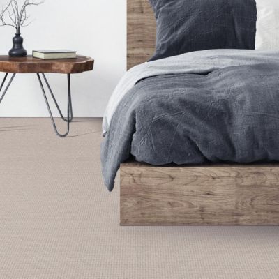 soft beige carpets in a rustic bedroom with wood bed frame and live edge side table