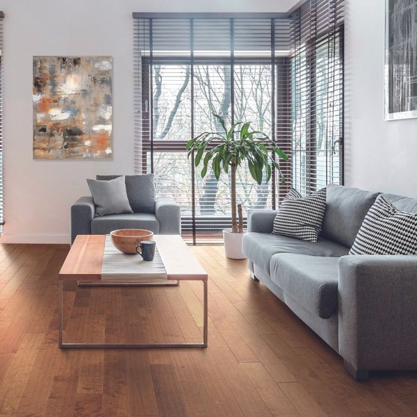 hardwood flooring in a bright living room with large windows and grey couches